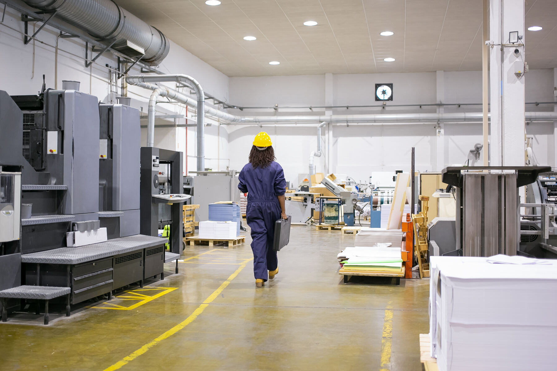 A team member in a hard hat walking the production floor of a manufacturing plant